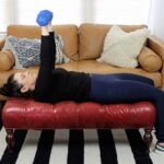 A woman working out with dumbbells in her living room