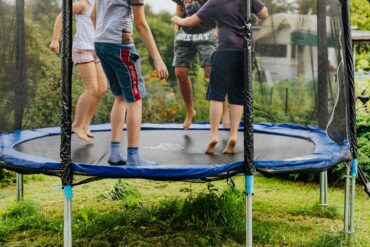 3 children playing on a home style trampoline on a summer day