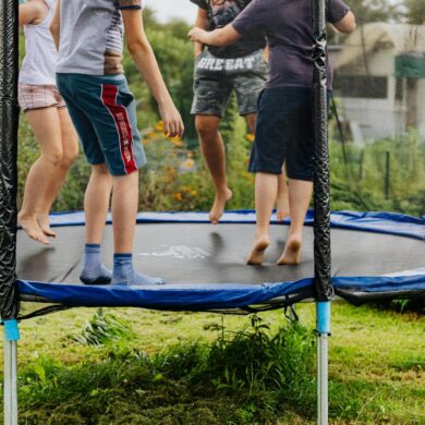 3 children playing on a home style trampoline on a summer day