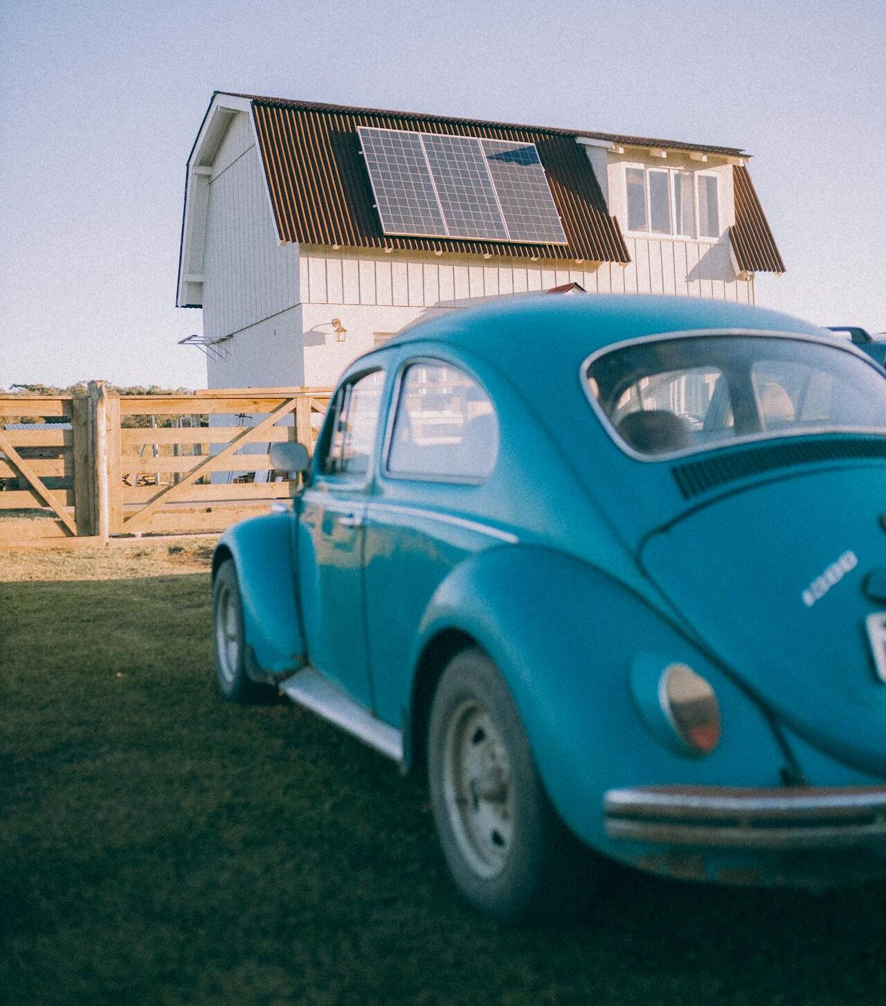 a vacation home with solar panels on the roof, farmhouse style with a vintage vw bug in front.