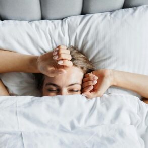 A woman in bed in the early morning. She's just waking up and beginning to stretch.