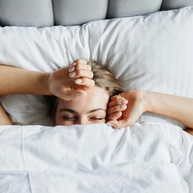 A woman in bed in the early morning. She's just waking up and beginning to stretch.