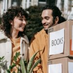 a man and woman moving boxes outside after decluttering their home before a big move