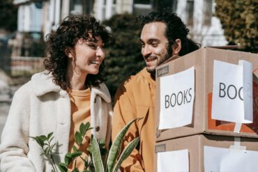 a man and woman moving boxes outside after decluttering their home before a big move