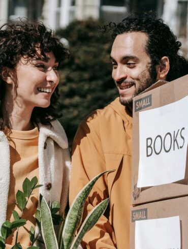 a man and woman moving boxes outside after decluttering their home before a big move