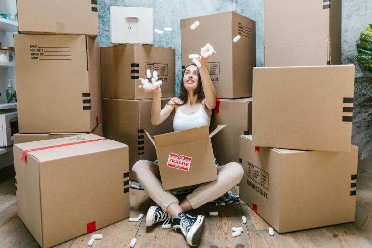 a woman surrounded by moving boxes and throwing packing peanuts into the air