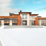A modern home with large floor to ceiling windows, warm wood cladding, and a clean entryway, surrounded by snow on a bright winter day, showcasing how upgraded glazing and entryways can transform a home's curb appeal.