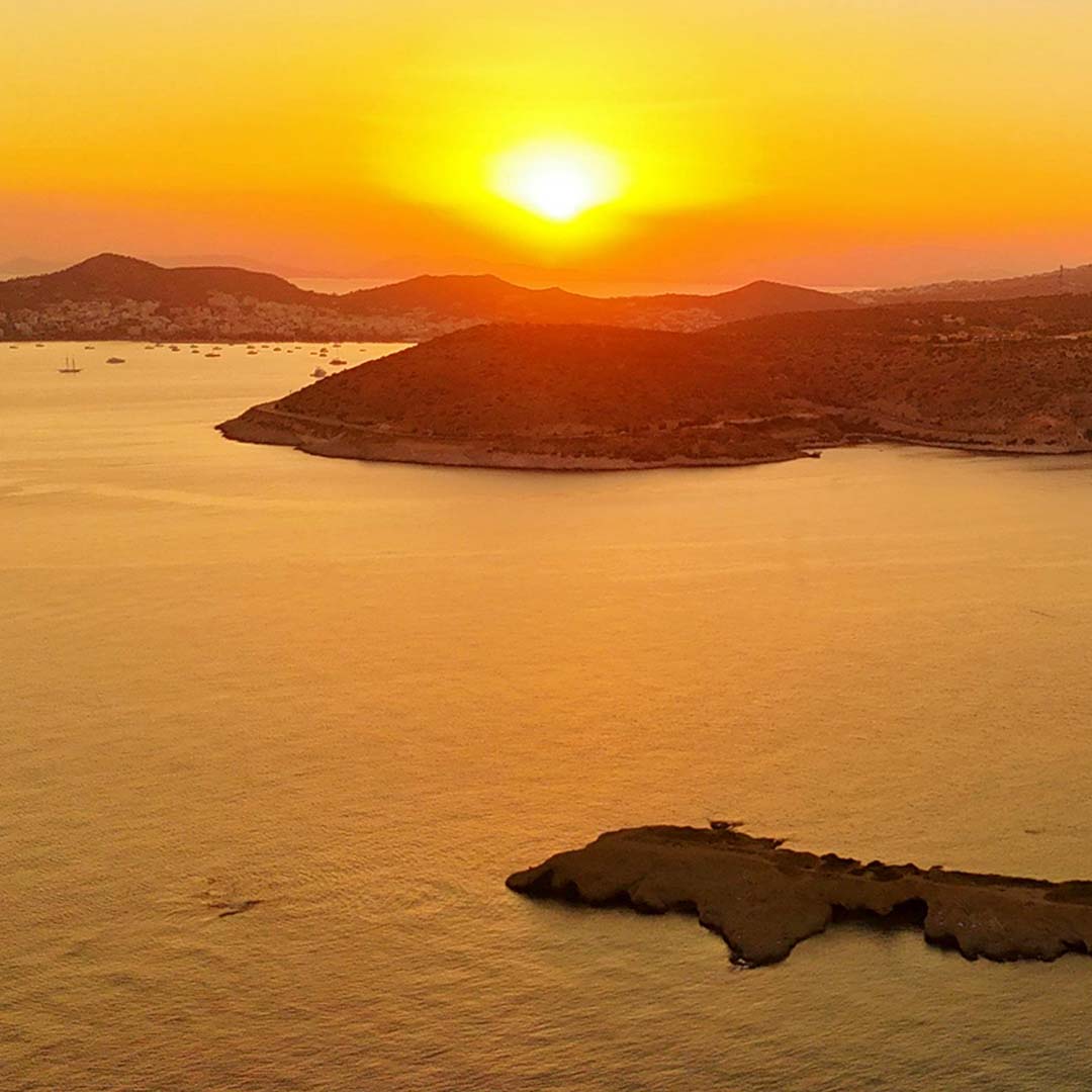 Aerial shot at sunset of the Greek islands and mountains over the sea.