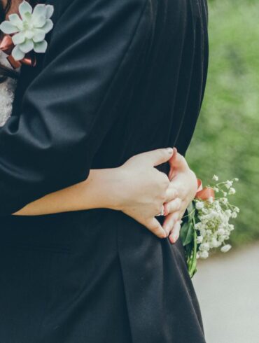 Bride and groom embrace holding white flowers on wedding day, planning an affordable and beautiful stress-free celebration