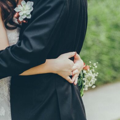 Bride and groom embrace holding white flowers on wedding day, planning an affordable and beautiful stress-free celebration