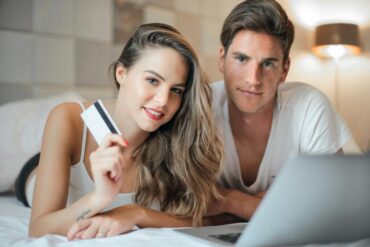 Young couple researching wellness financing options and payment plans for self-care services while reviewing wellness credit card alternatives on laptop at home