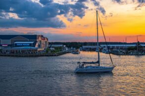 Romantic sunset over Kent Narrows Maryland with sailboat anchored in calm water and waterfront restaurants along the Chesapeake Bay creating intimate atmosphere for couples
