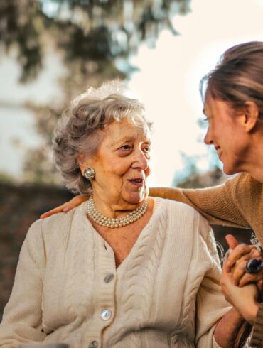 Joyful adult daughter greeting happy surprised senior mother in garden