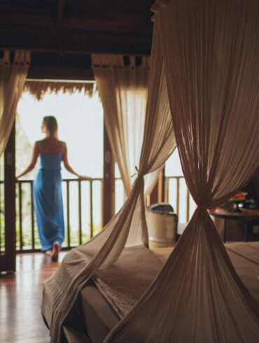 Woman Leaning on Handrail in a cozy and warmly lit lux bedroom