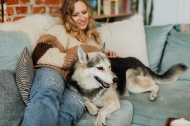 a woman at home on her sofa, relaxing with her dog