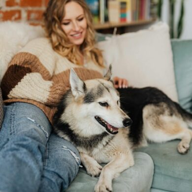 a woman at home on her sofa, relaxing with her dog