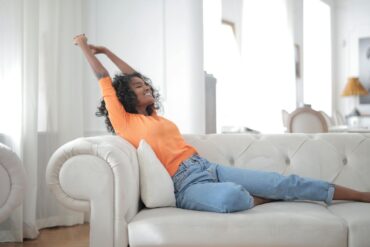 a woman relaxing on her couch in a clean brightly lit house with no clutter