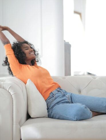a woman relaxing on her couch in a clean brightly lit house with no clutter