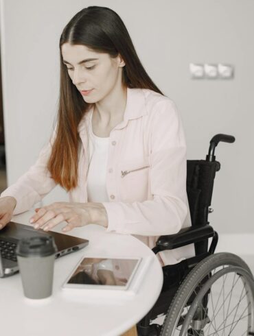 Woman in a wheelchair using a laptop at a kitchen counter in an accessible home