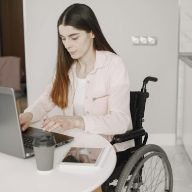 Woman in a wheelchair using a laptop at a kitchen counter in an accessible home