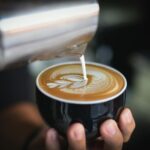 a person making a delicious cappuccino for a client