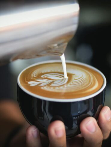 a person making a delicious cappuccino for a client