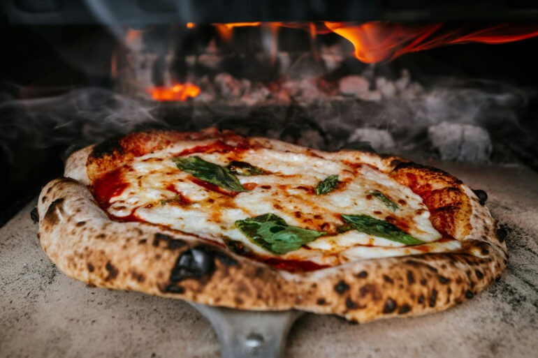 a fresh authentic italian pizza coming our of a real wood fired oven.