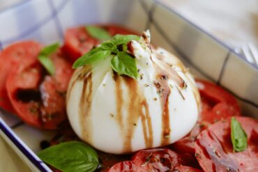 a portion of fresh mozzarella cheese over tomato and basil dressed with balsamic