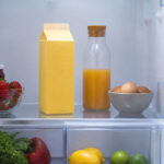 Eye-level shot of an open refrigerator interior. A quart carton of buttermilk stands upright on the middle interior shelf, centered in frame