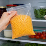 someone taking a plastic bag of shredded cheese from the fridge