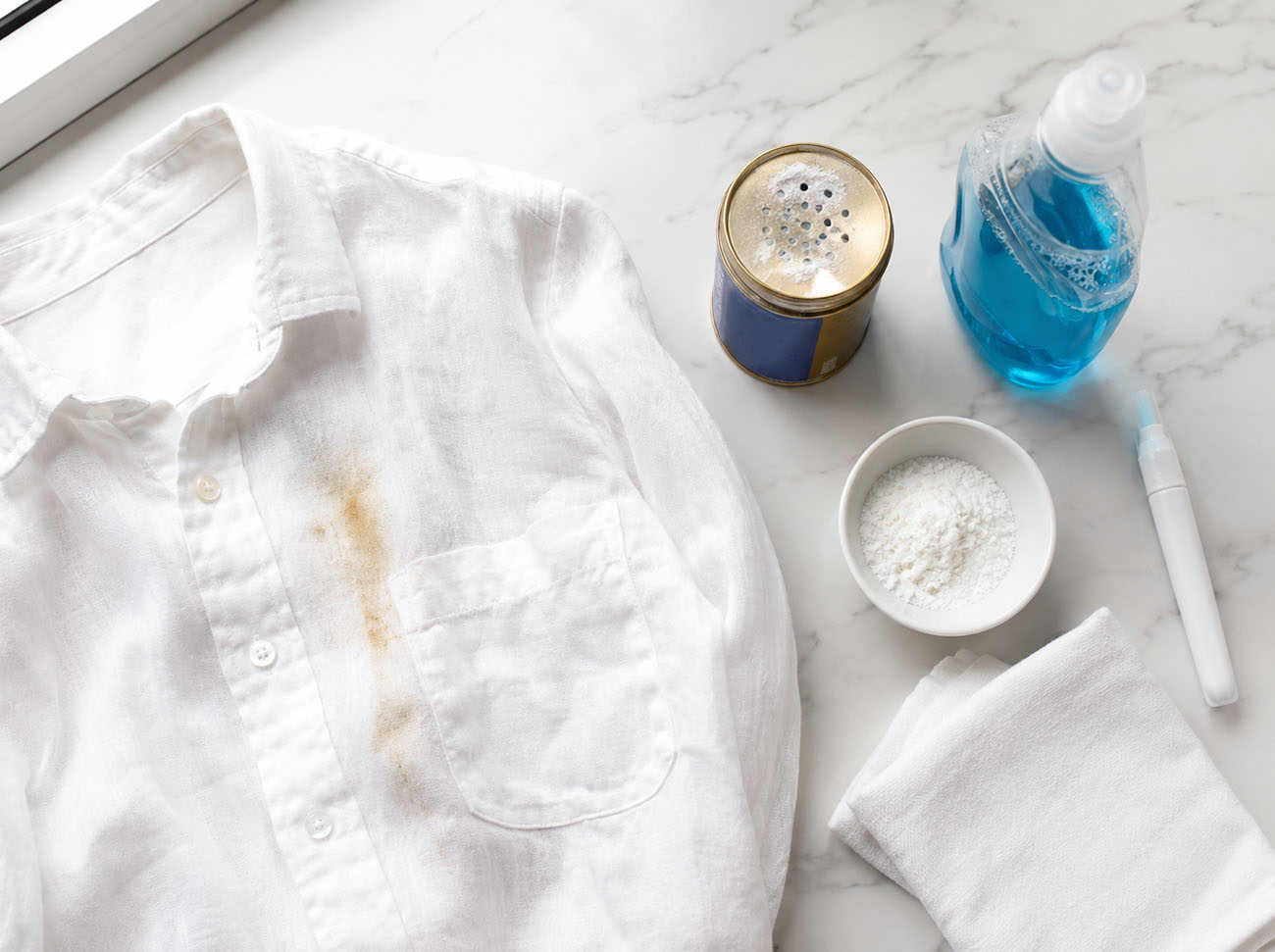 a white linen shirt with an orange sunscreen stain. cleaning supplies trying to remove it.
