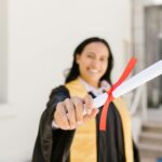 A happy graduate proudly displays her diploma in an outdoor setting, symbolizing achievement.