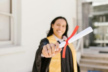 A happy graduate proudly displays her diploma in an outdoor setting, symbolizing achievement.