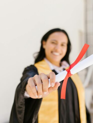 A happy graduate proudly displays her diploma in an outdoor setting, symbolizing achievement.