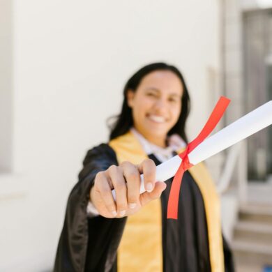 A happy graduate proudly displays her diploma in an outdoor setting, symbolizing achievement.