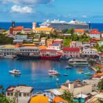 Views of the vibrant harbor in St. George's, Grenada. Colorful buildings and boats can be seen under the bright blue sky.