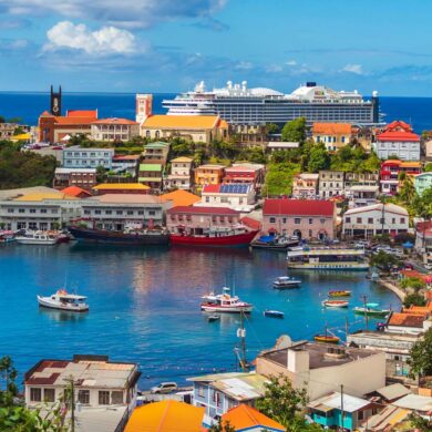 Vibrant harbor view in St. George's, Grenada with colorful buildings and boats under a bright blue sky.