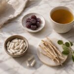 Flat lay of natural sleep supplements on a warm white marble surface, magnesium capsules, a small dish of CBD gummies, a sprig of ashwagandha root, and a cup of herbal tea, soft natural morning light from the side, clean and minimal lifestyle photography, muted earth tones