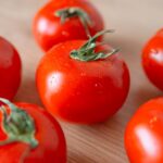 Close-up of fresh cherry tomatoes with dewdrops on a wooden surface, highlighting freshness and deliciousness