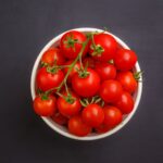Flat lay of fresh cherry tomatoes in a white bowl against a gray backdrop