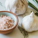 garlic bulbs on a counter with a bowl of minced garlic