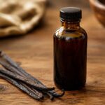 Dark amber glass bottle of pure vanilla extract with vanilla beans beside it on a wooden surface