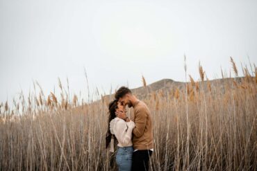 A man and a woman standing in a field of tall grass This couple was so in love as they explored the beautiful nature around them.