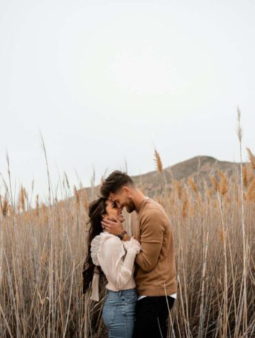 A man and a woman standing in a field of tall grass This couple was so in love as they explored the beautiful nature around them.