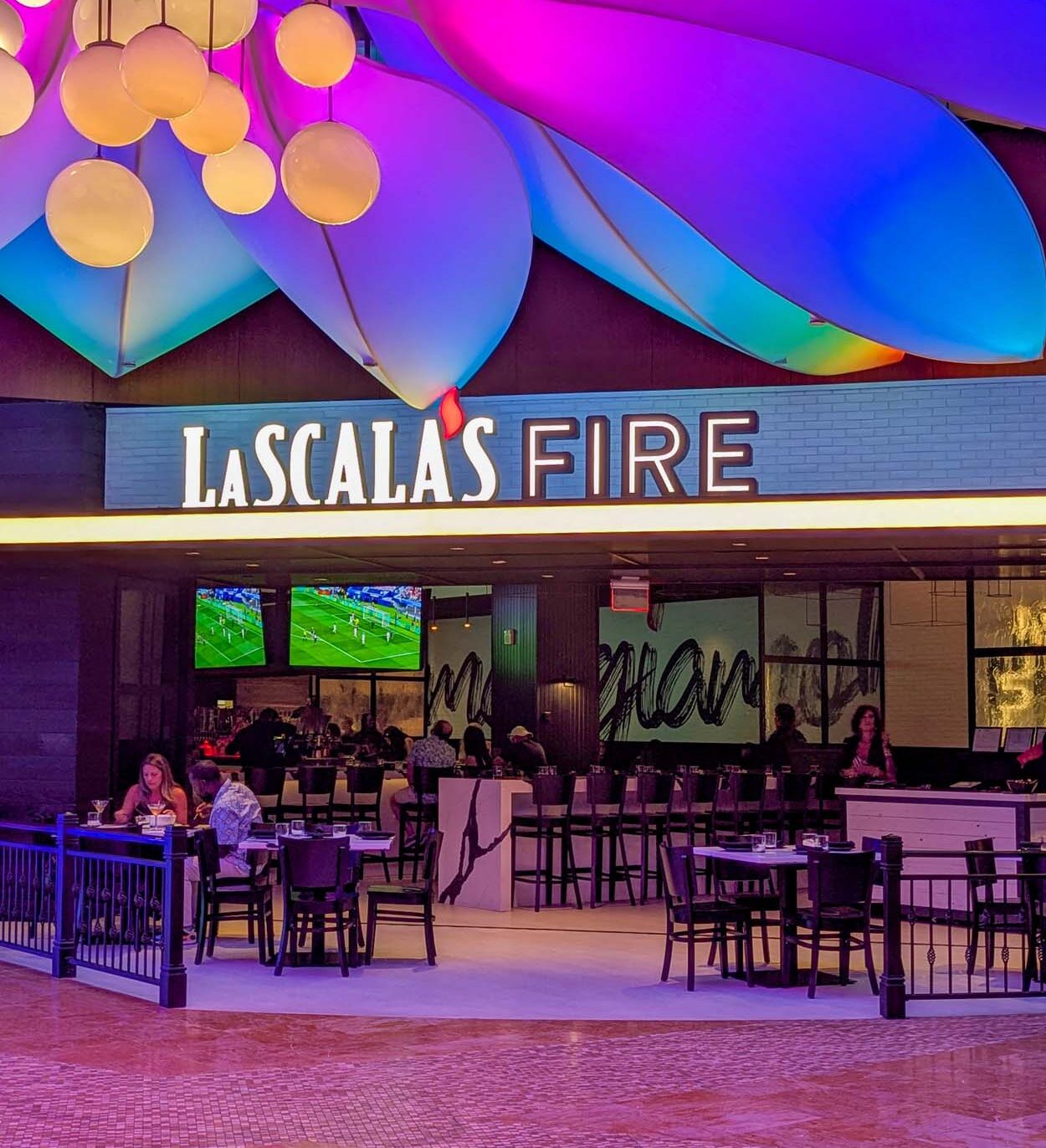 LaScala's Fire restaurant entrance at Ocean Casino Resort with glowing illuminated sign and colorful flowing ceiling art installation in purple, blue, and pink