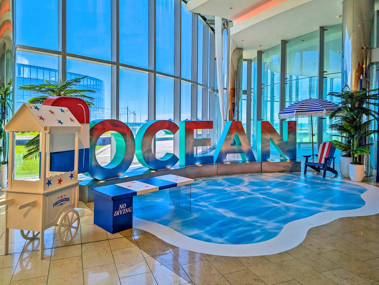 Ocean Casino Resort lobby with large red, white, and blue OCEAN letter installation, Americana beach décor, and a firecracker pops cart for America's 250th celebration