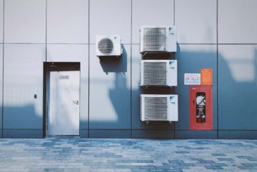multiple commercial hvac systems installed on a building next to a door.