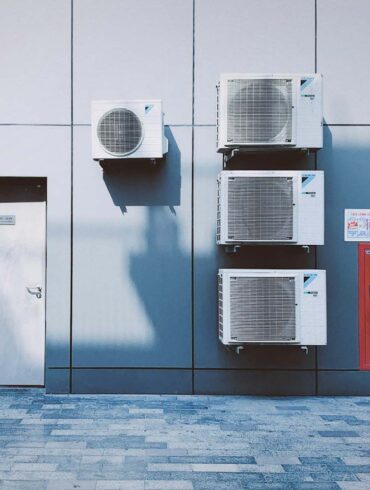 multiple commercial hvac systems installed on a building next to a door.