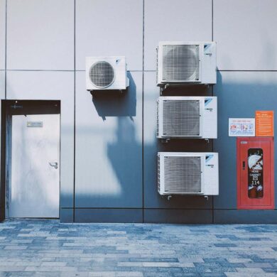 multiple commercial hvac systems installed on a building next to a door.