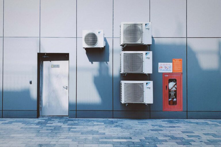 multiple commercial hvac systems installed on a building next to a door.